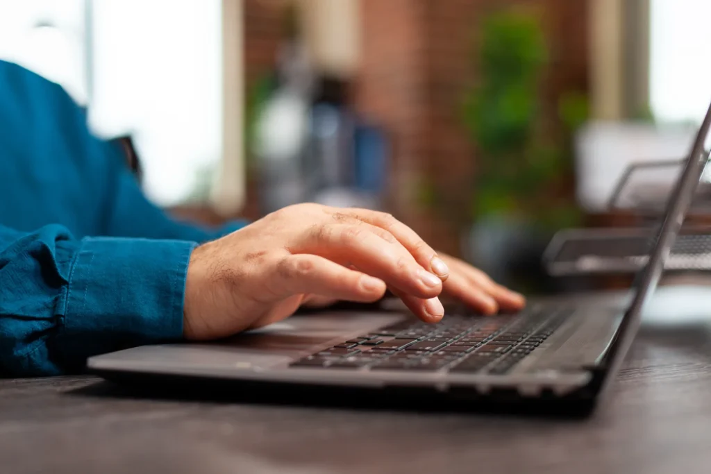 Kéz laptopon gépel az irodában
